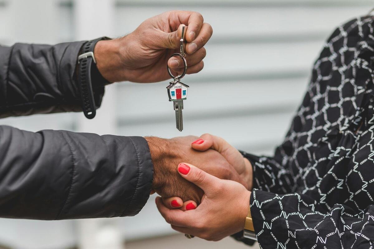 Handshake and keys exchanging, signifying property ownership, a deal closed, or a new home.